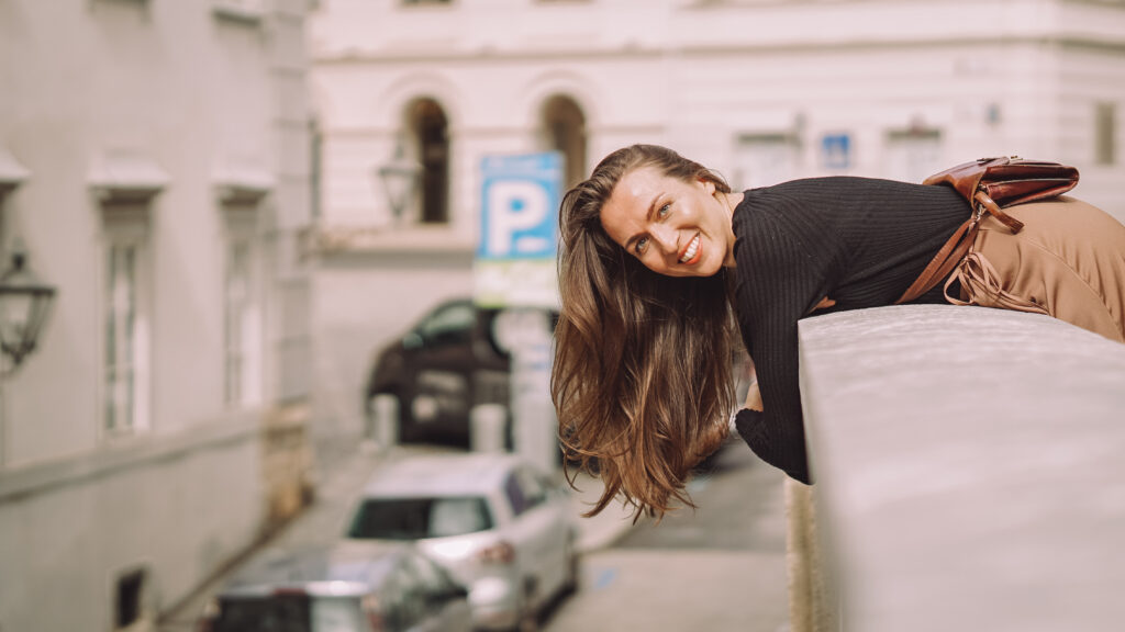 Frau mit braunen Haaren lehnt sich über die Mauer mit Grazer Altstadt im Hintergrund