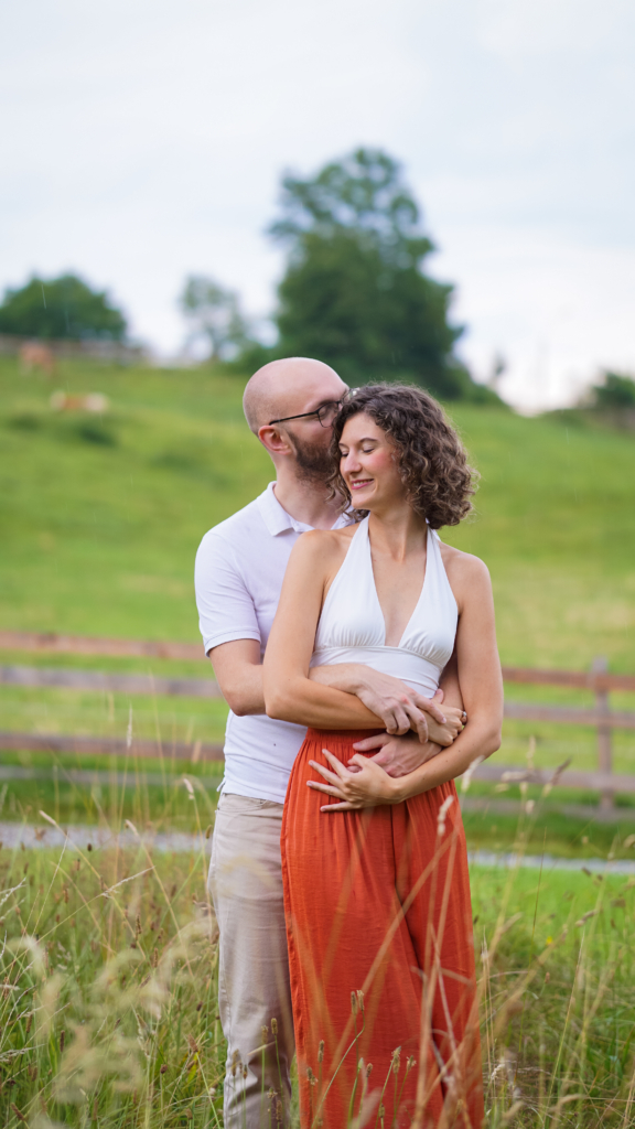 Mann küsst Frau auf den Hinterkopf, schöne grüne Landschaft im Hintergrund in Graz Lustbühel 