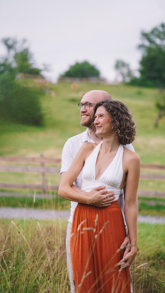 Mann umarmt Frau von hinten. Paar-Portrait im Grünen in Graz