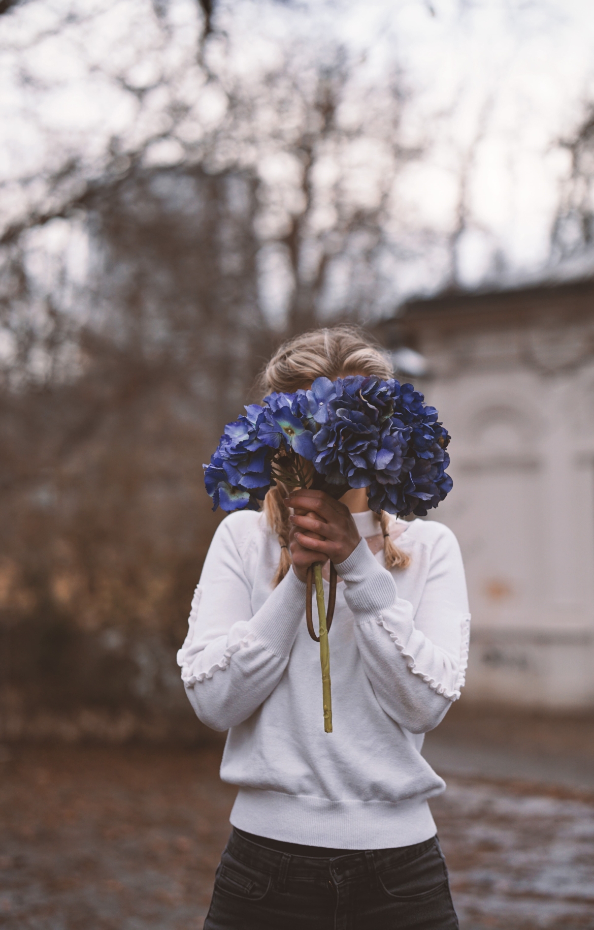 Portraitshooting, bei dem Frau Blumen vor Gesicht hält.
