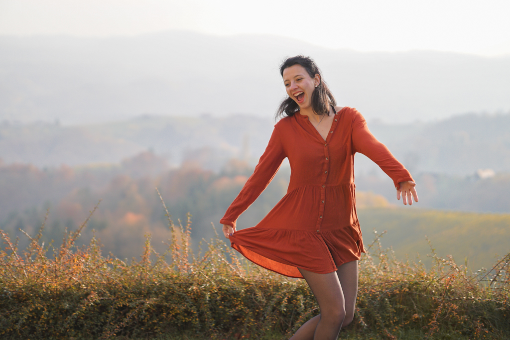 Frau mit orangem Kleid im Herbst in der Südsteiermark bei Sonnenuntergang mit Weinbergen